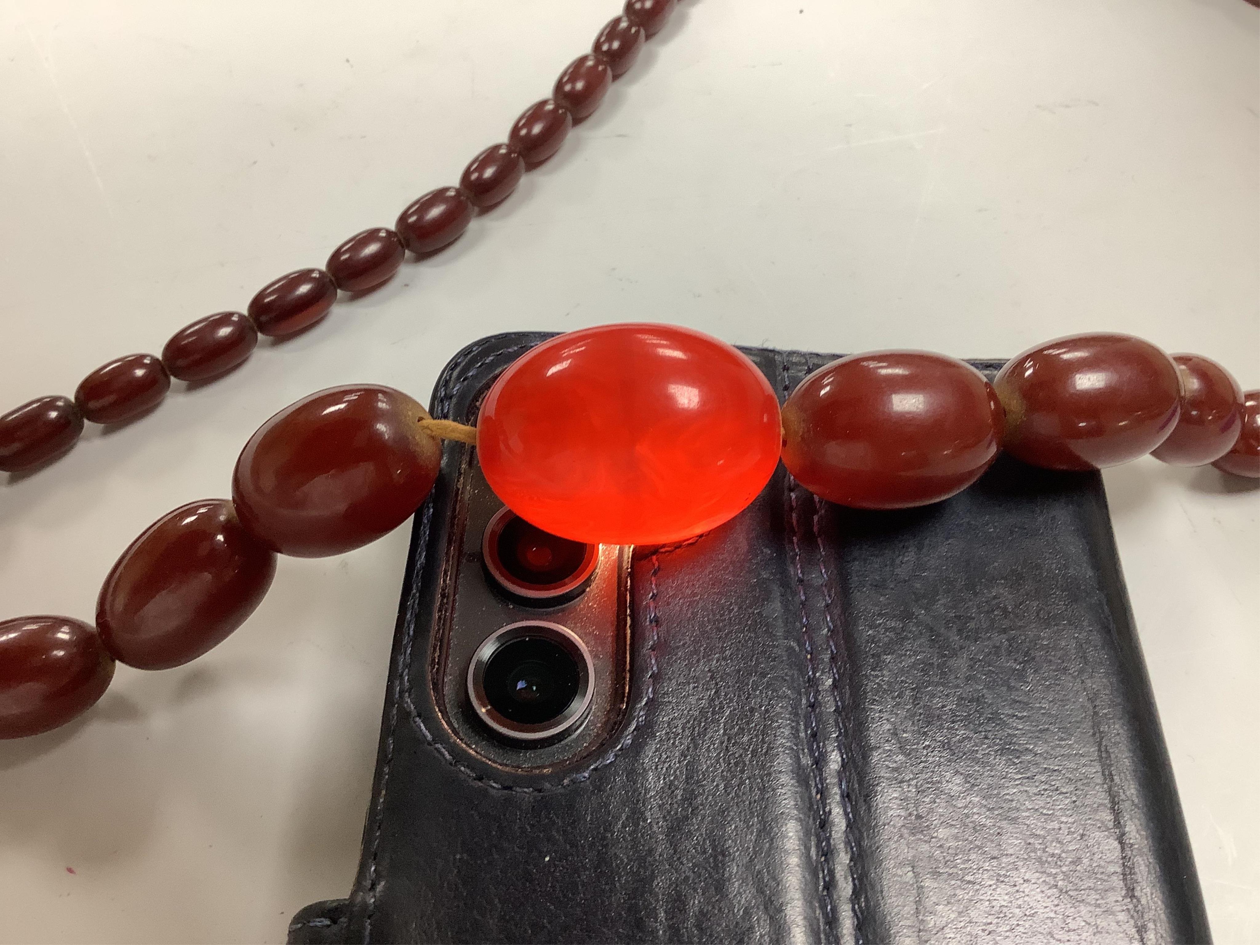 A cherry-coloured bakelite 'amber' necklace, composed of graduated oval beads measuring approximately 1.1-3cm, length 76cm, gross weight 66 grams, Condition: good, minor wear
